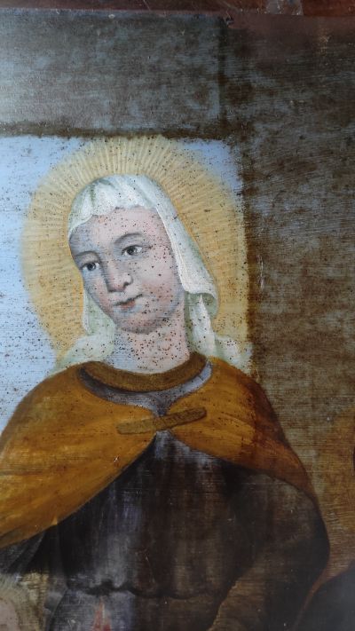 Fragment obrazu na blasze z przedstawieniem Św. Zofii. Etap chemicznego usuwania zbrązowiałej, pociemniałej warstwy pokostu, kt&oacute;rym pokryty został obraz. Odsłania się pierwotna, żywa kolorystyka. Jednocześnie widać skalę korozji metalowego podłoża, na kt&oacute;rym namalowany został obraz oraz całą masę drobnych ubytk&oacute;w warstwy malarskiej. Fot. ze zbior&oacute;w autorki